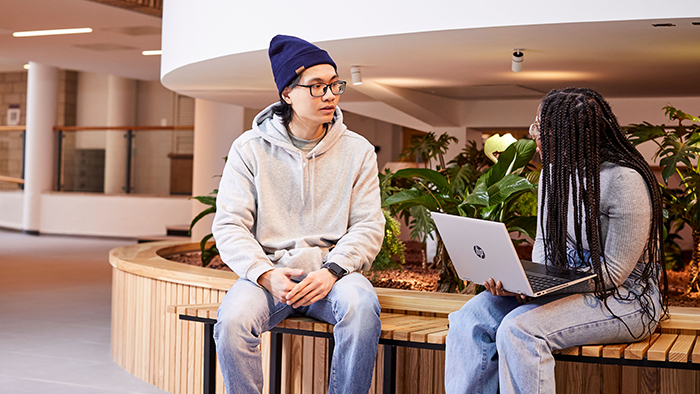 Two students, one male and one female, are chilling in the Atrium.