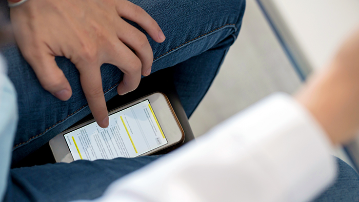 A close up of a student hiding a mobile phone between their legs during an exam.