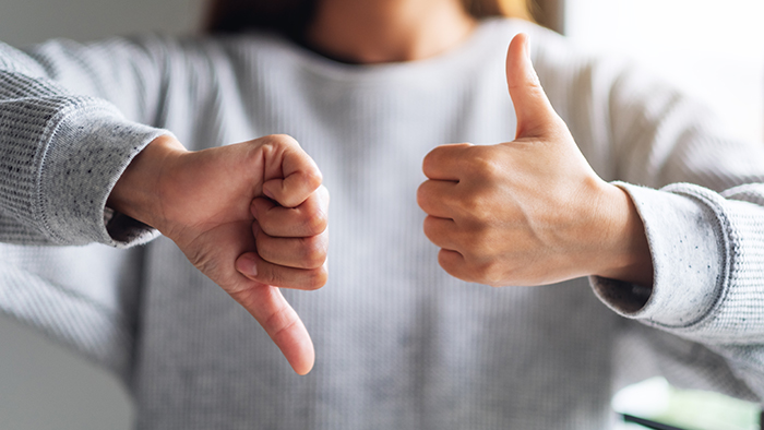 A woman's hands, one giving a thumbs up and one giving a thumbs down