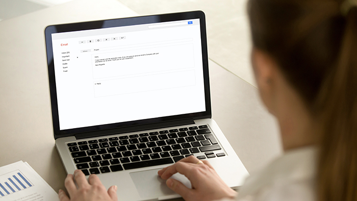 A view over the shoulder of someone composing an email on a laptop.