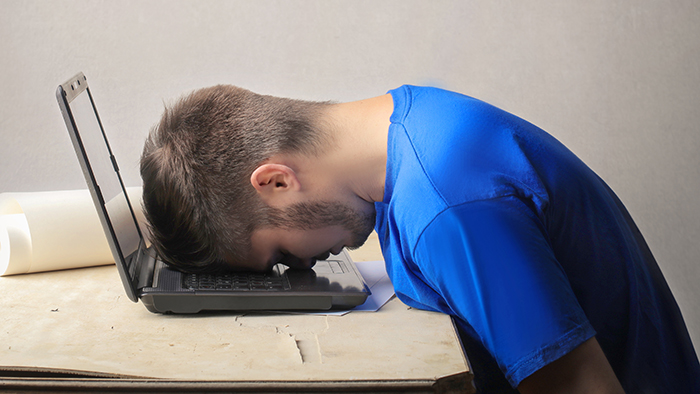 A student resting their head on a laptop keyboard