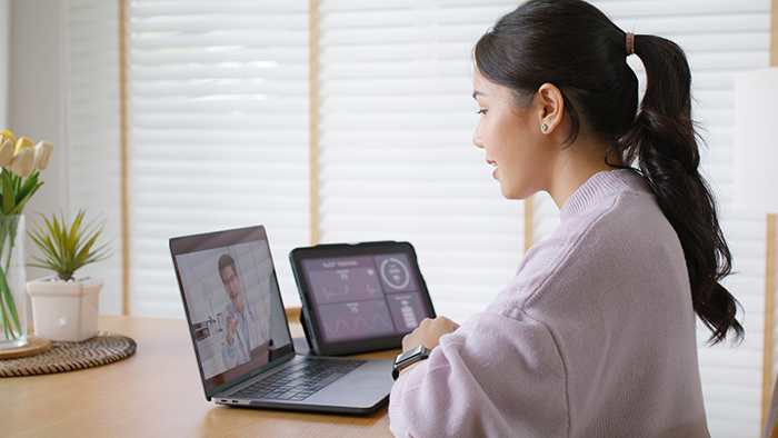 A student on a video call with a smaller tablet-type device next to the screen. 