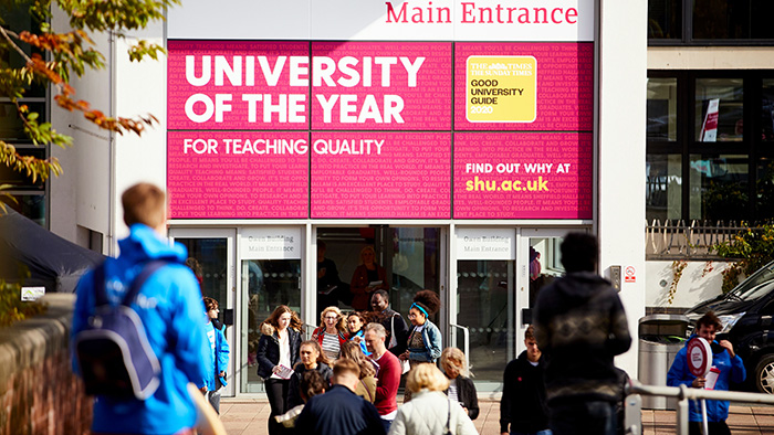 A view of the outside of Owen Building on a sunny day. Above the entrance is a sign that reads "University of the Year for Teaching Quality"