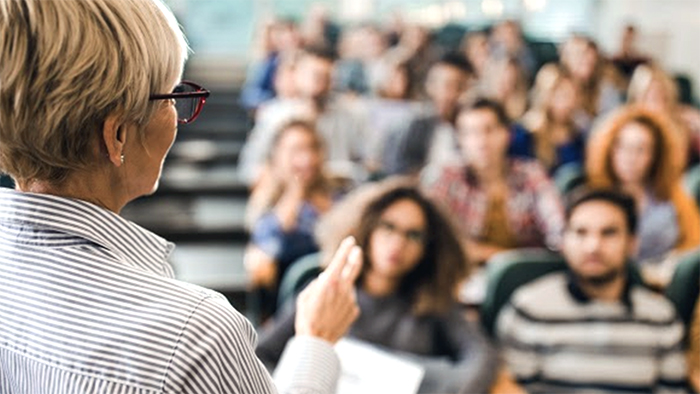 A lecturer is teaching a class. The students look on with undivided attention.