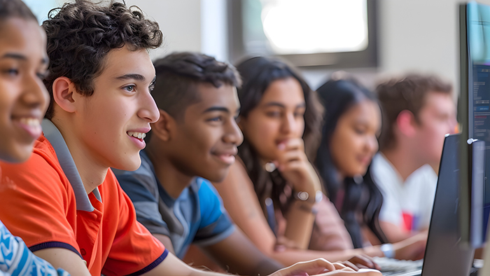 A row of students, of various ethnic backgrounds, looking at computer screens. 