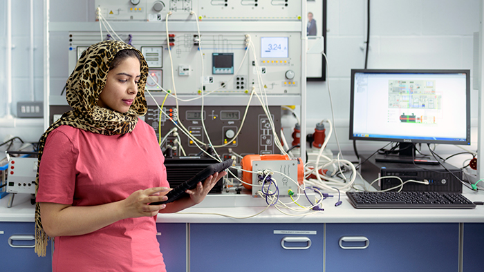 A student in a colourful hijab works in a laboratory.