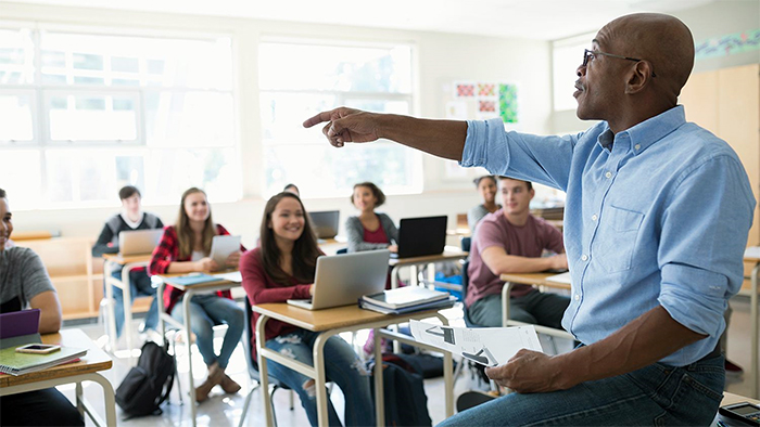 A smiling lecturer teaches some interested students.