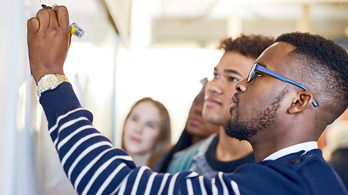 A group of students are writing on a whiteboard.