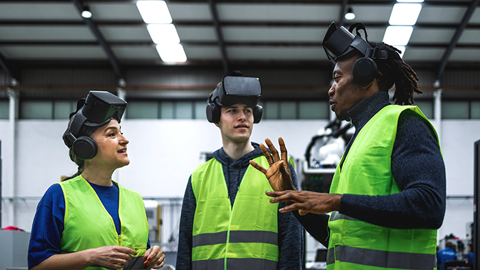 Three students in high-vis jackets wearing virtual reality headsets