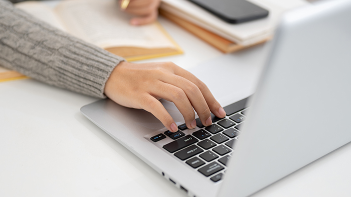 Hands typing on a laptop