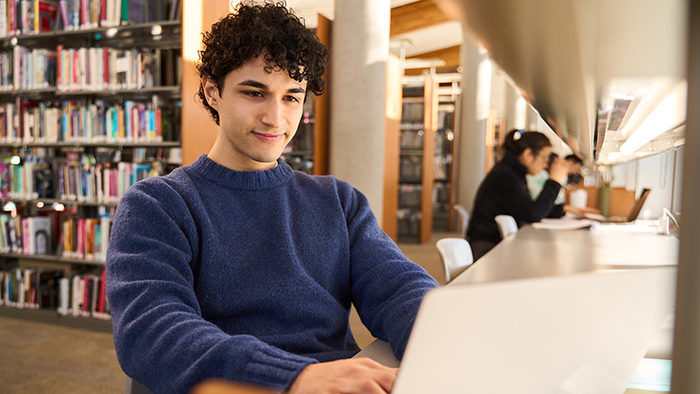 A male student using a laptop in a library