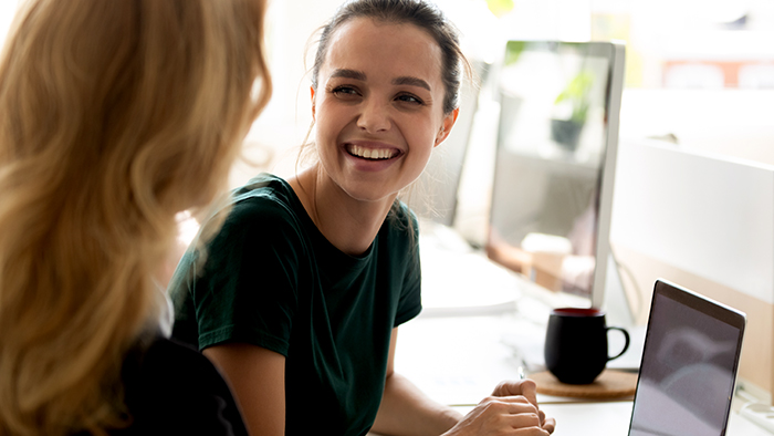 A smiling young lady being helped at a computer 