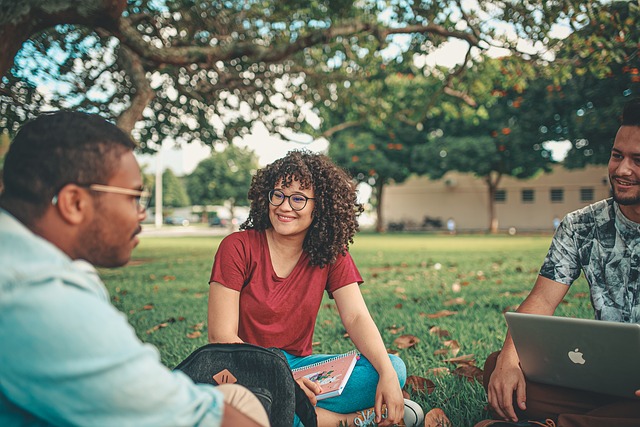 Image of three students sitting on the grass talking