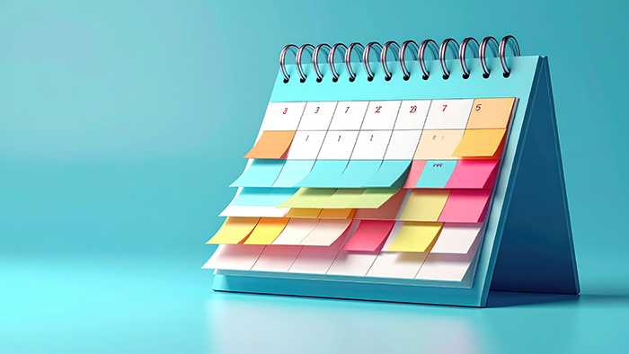 A brightly coloured desk calendar with sticky notes attached to many of the dates.