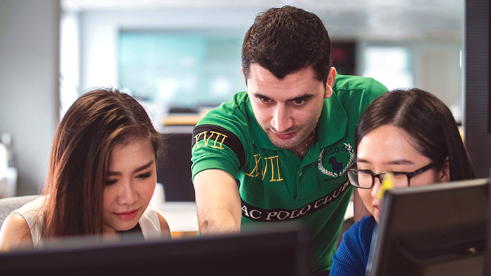 Three students intently gathered around a computer.