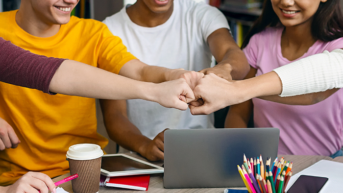 Students fist-bumping each other and smiling