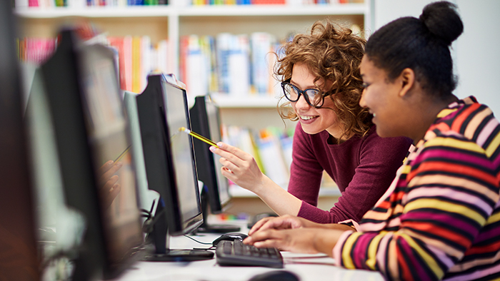 A teacher and student working on a computer together