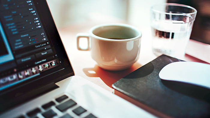 A cup of coffee next to a laptop.