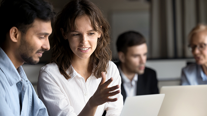 A woman explaining something to a man using a laptop