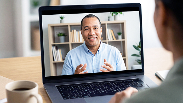 A view over someone's shoulder at their laptop screen. It looks like a video call with someone else, or it could be a recorded training video. 