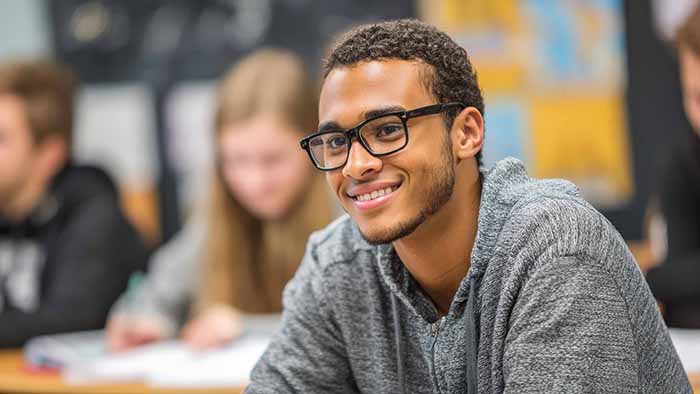 a closeup of a smiling student in a busy classroom