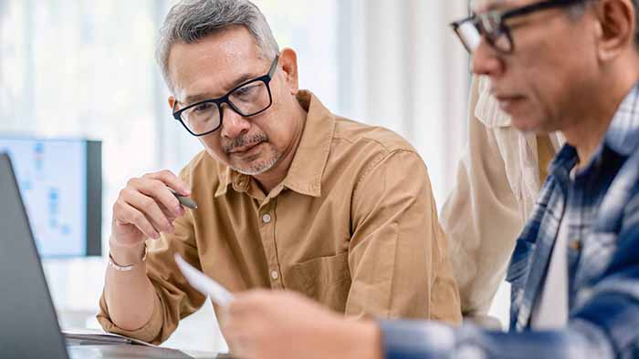Two serious looking men are working together on an open laptop
