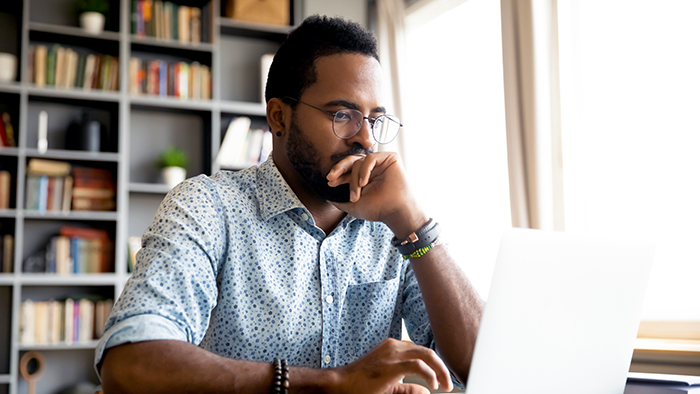 An adult male concentrating on a laptop. The background looks like a smart home office.