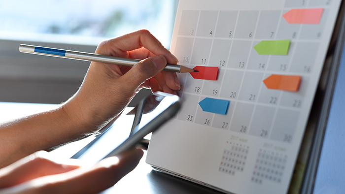 A desk calendar with sticky notes on some of the dates