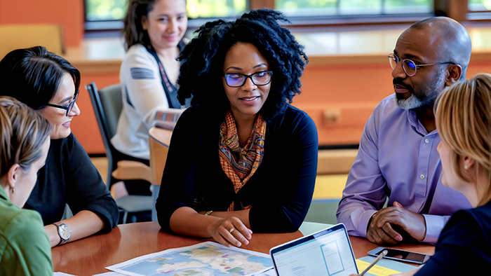 A group of six academics, of various ethnic backgrounds, discussing something around a table.