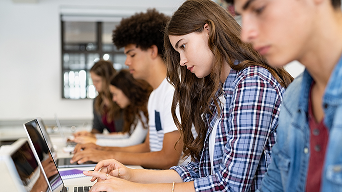 A row of students, working and concentrating on their laptops.