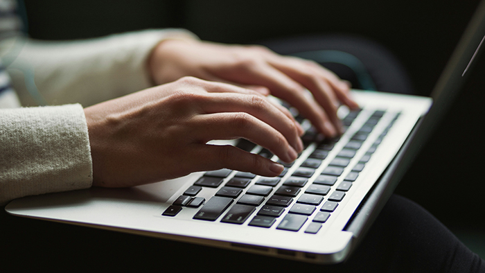 Hands typing on a laptop.