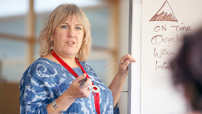 A close up of a female lecturer addressing a small group of people.