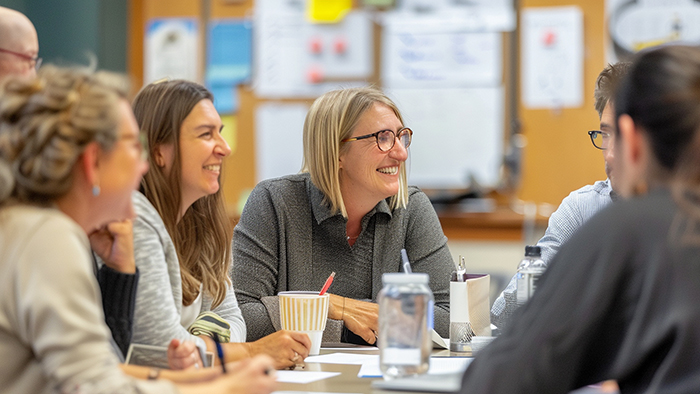 A group of academics sitting around a table and chatting happily.